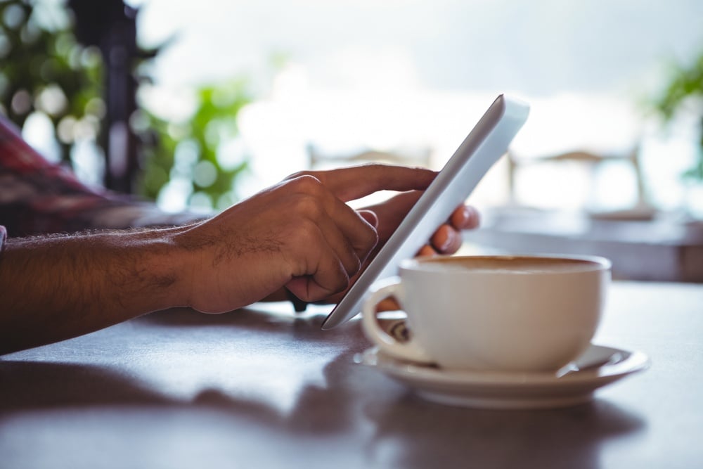 Hands of man using digital tablet in cafeteria